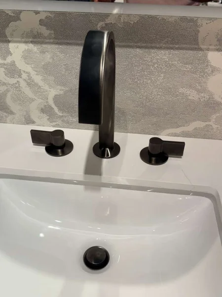 A matte-black tap and separate controls paired with a white basin.