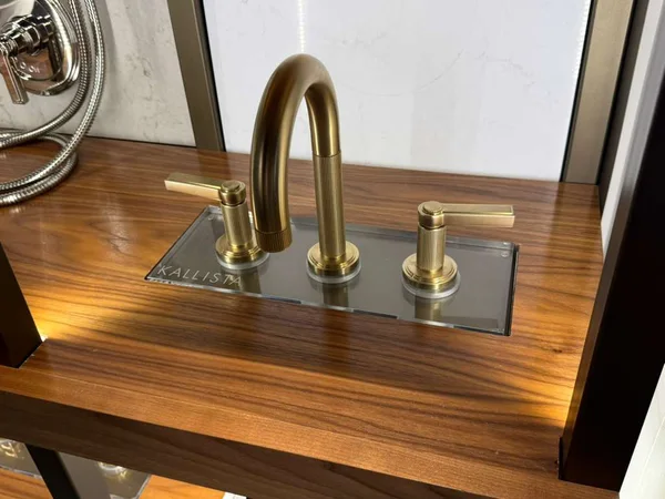 A warm brass-finish tap with separate handles, shown on a timber display.